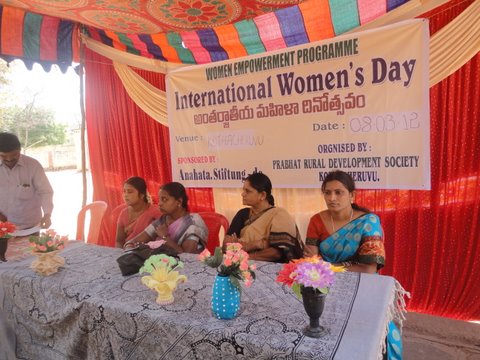 Four women sit on an improvised stage